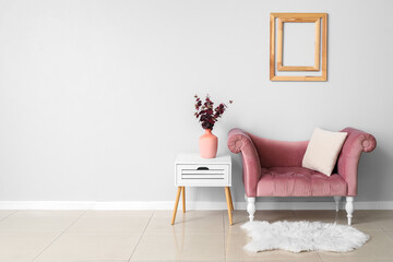 New sofa and vase with flowers on table near light wall