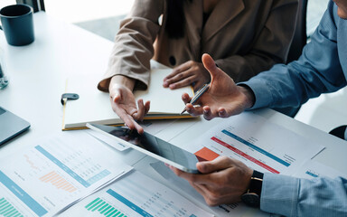 Close up two business partnership coworkers discussing a financial planning on digital tablet and...