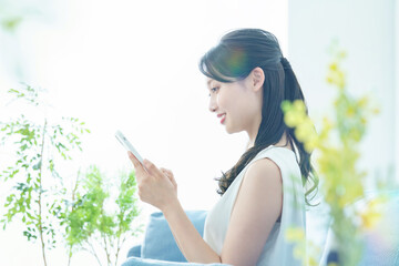 明るい部屋でスマートフォンを操作する女性