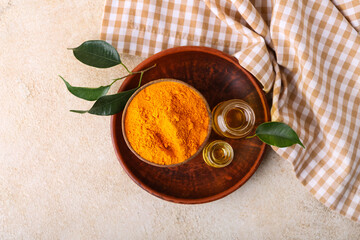 Bottles of oil and turmeric powder on light background
