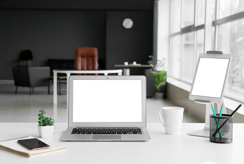 Workplace with modern laptop, tablet computer and mobile phone in office
