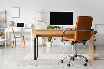 Workplace with modern computer and comfortable chair in light office