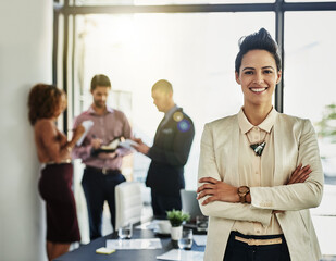 Ive got full confidence in my team. Portrait of a businesswoman standing with her arms folded while some colleagues talk in the background.