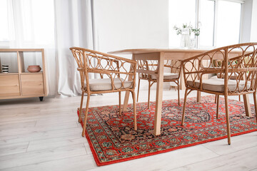 Interior of light dining room with table and vintage carpet