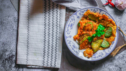 Fried Solanum melongena with Egg in a green dish on the table with garlic, dried chilli