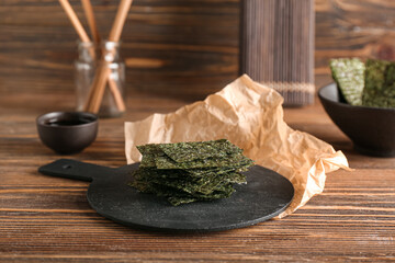 Board of tasty seaweed sheets on wooden background © Pixel-Shot