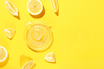 Composition with cut ripe lemons and juicer on yellow background