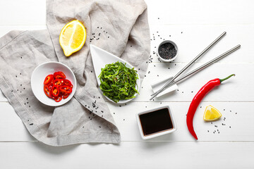 Plate with healthy seaweed salad and ingredients on light wooden background © Pixel-Shot