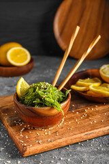 Bowl with healthy seaweed salad, lemon and sesame on grey grunge background