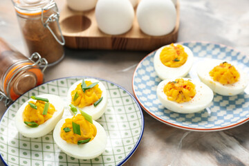 Plates with stuffed eggs and spices on grunge background, closeup. Easter celebration
