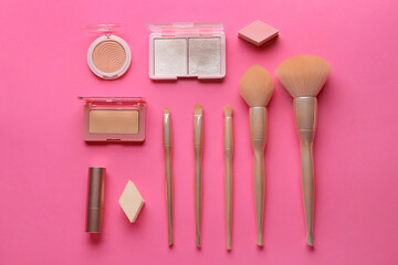 Composition with cosmetic products and makeup brushes on pink background, top view