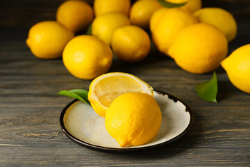 Plate with ripe lemons on table