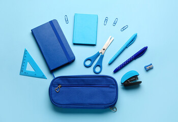 Pencil case with school stationery on blue background, top view