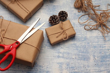 Fototapeta na wymiar gift wrapping from Kraft paper wrapped with twine, the concept of handmade, light blue tabletop.