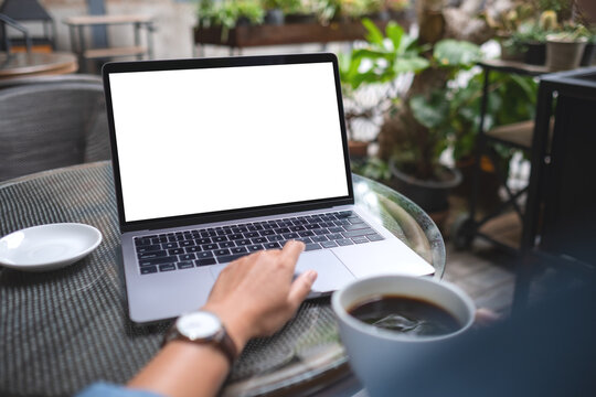 Mockup image of a woman using and working on laptop computer with blank white desktop screen while drinking coffee in the outdoors
