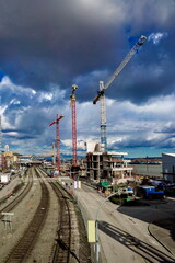 Fototapeta na wymiar Waterfront of Fraser River, Residential district in Downtown of New Westminster, construction site along the river bank, three construction cranes, traffic on the road. Spring time