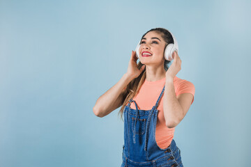 hispanic young woman with headphones, dancing and listening music on blue background in Mexico Latin America	