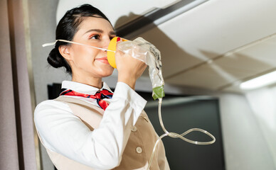 female flight attendant wearing a breathing apparatus demonstrates safety gear in the cabin before...