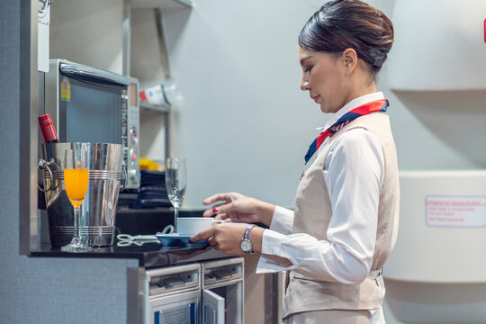 Female flight attendant in the cabin prepares lunch and refreshments for the passengers on board.Airline Service and traveler Concept
