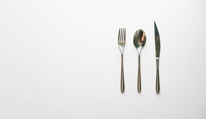 set of metal cultery equipment on the white table, spoon, fork and knife