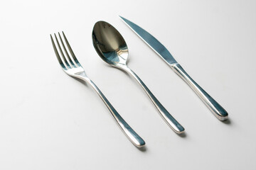 set of metal cultery equipment on the white table, spoon, fork and knife