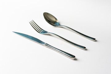set of metal cultery equipment on the white table, spoon, fork and knife