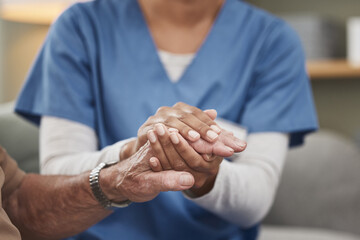 Heroes wear scrubs too. Shot of an unrecognizable nurse holding a patients hand during a checkup at home. - Powered by Adobe
