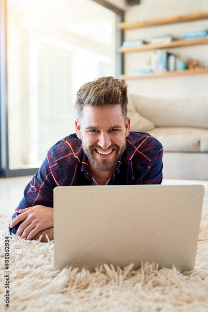 Poster i make time for a bit of mellowness. shot of a relaxed young man using a laptop on the floor at home