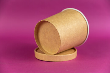 Empty cylindrical paper container with lid opposite-colored background. Brown food container for soup, ice cream, noodles, or other food.