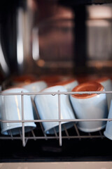 The process of washing yogrut jars in the dishwasher. Homemade yogurt making. Vertical photo.