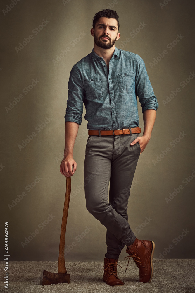 Poster dashing and daring. studio shot of a young man posing with an axe against a green background.