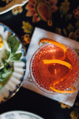 top down shot of orange cocktail with plate of snacks