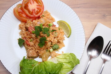 Pork and Sausage Fried Rice with Onions served in a white plate on a light wooden table.