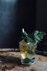 Mint julep bourbon whiskey cocktail in glass on barrel