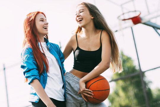 Two funny girls with a basketball hug each other after a game or workout. The concept of sports and friendship