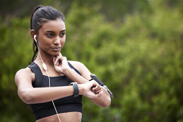Keeping count of her health. Shot of a sporty young woman checking her pulse while exercising outdoors.