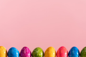 Easter eggs arranged in a single row on a solid pink background. Easter.