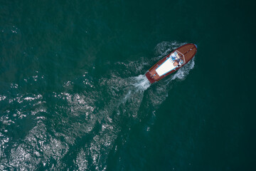 Classic wooden boat in motion drone view. People on an Italian wooden boat, top view. Old boat on Lake, Italy. - obrazy, fototapety, plakaty