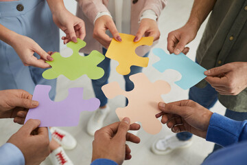 Teamwork with puzzle. Close up of male and female hands holding and folding together colorful pieces of puzzles. Concept of business, partnership, collaboration, teamwork, creativity, and innovation.