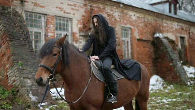 dramatic historical atmosphere of Middle Ages, dark haired bearded man is sitting on horseback