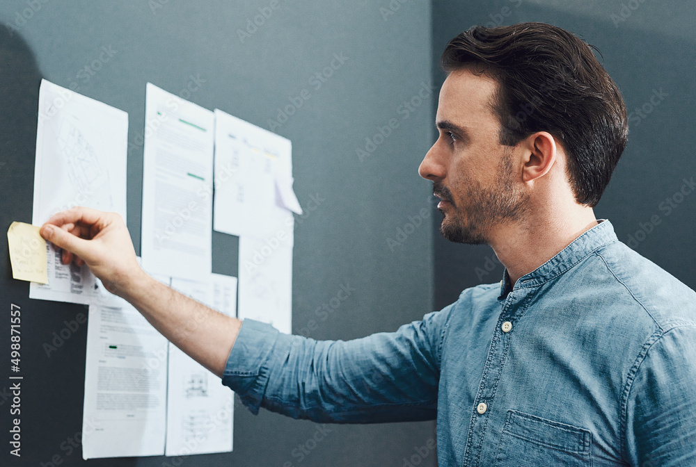 Poster whats next on his to-do list. cropped shot of a handsome young businessman reading a sticky note whi