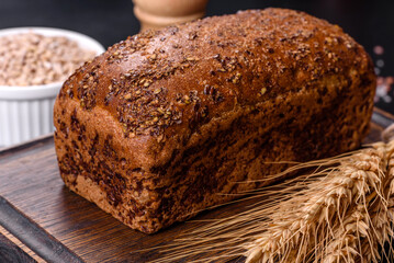 Fresh baked brown bread with ears and grains of wheat