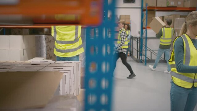 Team leader with digital tablet in busy distribution warehouse training female intern- shot in slow motion