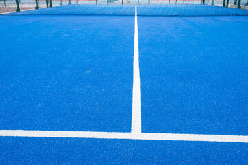 partial view of a blue turf paddle tennis court