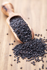 Bio natural black sesame seeds on wooden spoon.