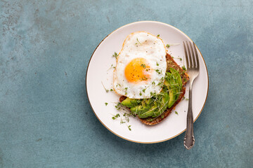 Keto breakfast fried egg, avocado and bread in a white plate. Keto diet concept.