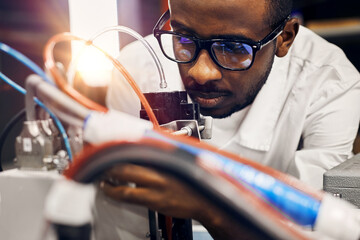 African engineer programming equipment with tablet at factory