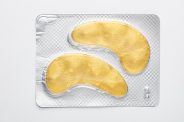 Gold hydrogel eye patches on white background.