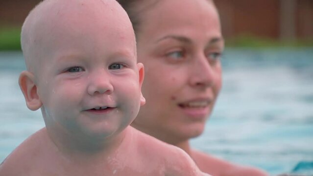 Happy kid swims in the pool. Parental health care.
