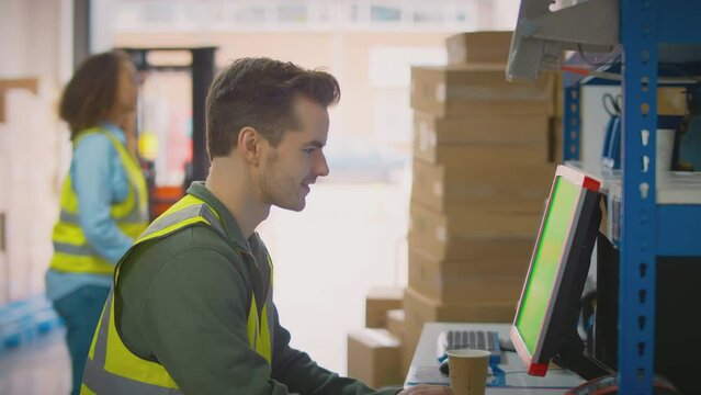 Male and female workers using computer terminals and moving boxes in distribution warehouse - shot in slow motion